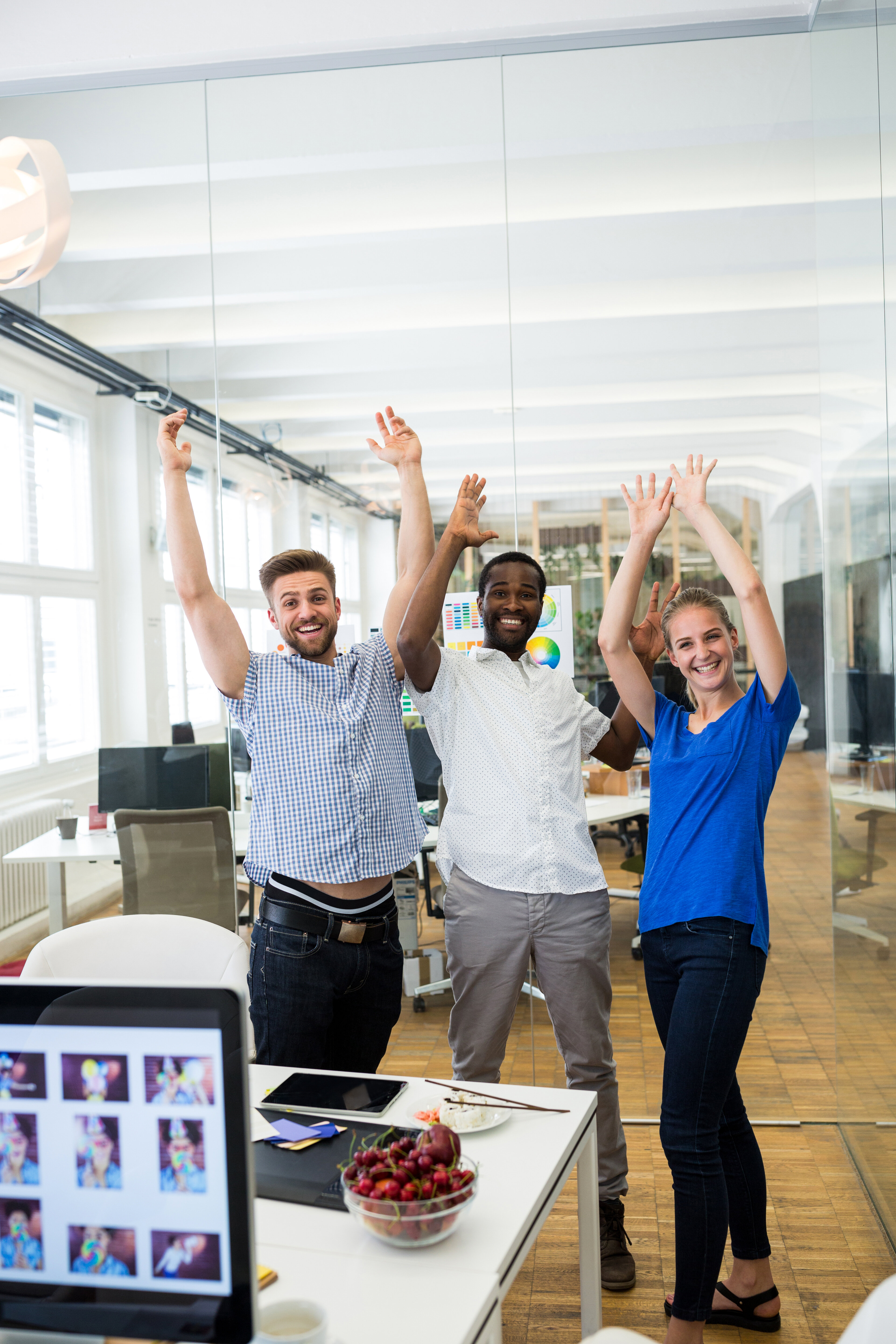 A group of UX designers in an office, celebrating and throwing their hands up in the air